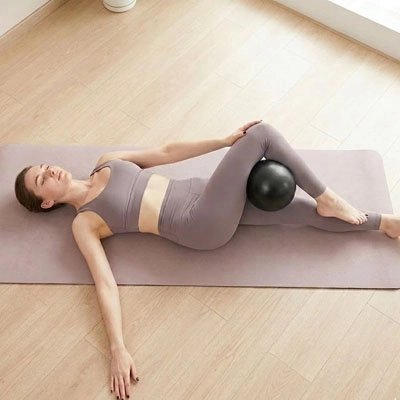 Ballon de pilates femme étirement des tendons fessiers et genou